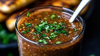 Rich brown lentil soup with fresh herbs in glass bowl, healthy vegetarian meal with spoon, warm comfort food for restaurant menu and cooking blogs.