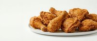 Crispy golden fried chicken pieces arranged on white plate against neutral background, ready for food photography, restaurant menus, and culinary content.
