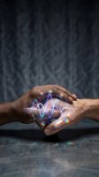 Cupped hands protecting glowing energy waves with rainbow light effects against dark textured background for spiritual and technology concepts.