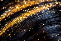 Shimmering golden glitter scattered on dark wavy surface creates magical abstract background with bokeh light effect and sparkling particles.