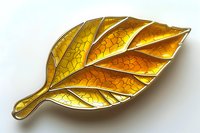 Golden autumn leaf brooch with honeycomb pattern and metallic shine, isolated on white background. Decorative jewelry piece featuring detailed veining and dimensional design.