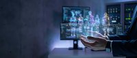 Businessman hand presenting holographic human figures in modern office with multiple monitors displaying data analytics and technology interface.
