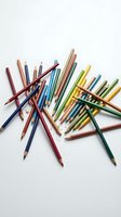Assorted colored pencils arranged in a scattered pattern on white background, showcasing various hues including red, blue, green, yellow, and brown for art, design, and creative projects.