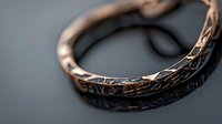 Vintage bronze ring with ornate engraved pattern and textured surface captured in macro photography against dark background showing intricate metalwork details.