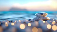Zen stone stack on beach pebbles with golden bokeh lights at sunset creating peaceful meditation atmosphere for wellness and mindfulness concepts.