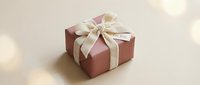Pink gift box with elegant cream ribbon bow and for you tag on beige background with soft bokeh lights for holiday celebration.
