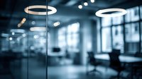 Modern office interior with circular lighting fixtures and glass partitions creating professional atmosphere in blue tones.