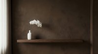 Minimalist interior shelf display with white ceramic vase and delicate flowers against textured brown wall, suitable for home decor and design projects.
