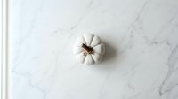 White garlic bulb isolated on marble surface, ready for culinary design, recipe graphics, food packaging, and kitchen-themed projects.