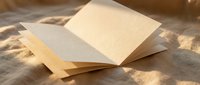 Open blank notebook with cream pages resting on linen fabric in warm sunlight, copy space for text or design mockup.