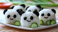 Cute panda-shaped rice balls with seaweed details and cucumber slices, arranged on white plate. Creative Asian food art for children's lunch, bento box styling.