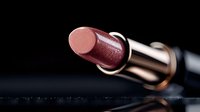 Pink metallic lipstick on dark background with reflection, luxury cosmetic product close-up macro photography for beauty and fashion advertising.