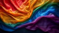 Vibrant rainbow colored smoke waves flow in dynamic motion against dark background, creating abstract fluid art pattern with smooth transitions between hues.
