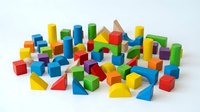 Colorful wooden building blocks scattered on white background featuring cubes, cylinders, triangles and geometric shapes for educational play and creativity.