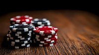 Stacks of red and black poker chips on rustic wooden table with dramatic lighting and shallow depth of field, creating moody gambling atmosphere.