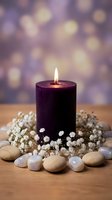 Purple candle burning with white flowers and smooth stones on wooden surface against soft bokeh background for spa relaxation and meditation atmosphere.