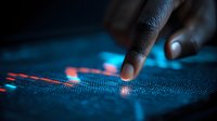 Finger touching digital stock market chart on glowing blue display with red indicators, showing financial data analysis and trading visualization.