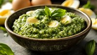 Creamy spinach dip with sliced eggs and fresh basil in rustic ceramic bowl, perfect for appetizers and party platters.