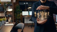 Professional businessman holding glowing holographic team figures in modern office environment representing human resources management and leadership concepts.