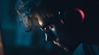 Dramatic profile of young man in dark moody lighting with blue and red color tones, creating atmospheric tension for cinematic or thriller content.
