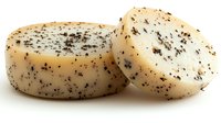 Creamy white cheese wheels with black pepper seasoning on surface photographed against white background, isolated food product for culinary and menu design.