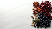 Festive winter spices and berries arrangement with cinnamon sticks, star anise, cranberries and blueberries on white background for holiday cooking.