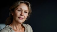 Portrait of mature woman with gentle smile against dark background, showcasing natural aging and confidence for wellness, healthcare, or retirement planning.