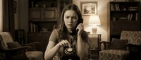 Young woman talking on vintage rotary phone in cozy retro living room with warm sepia tones and classic furniture creating nostalgic atmosphere.
