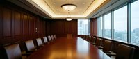 Executive boardroom with polished wooden table and leather chairs overlooking city skyline through floor-to-ceiling windows for corporate meetings.