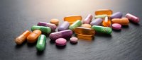 Colorful pharmaceutical pills and capsules scattered on dark surface for medical healthcare and medication concepts.