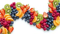 Fresh mixed berries and sliced fruits arranged in colorful pattern on white background. Healthy organic food ingredients for smoothies and desserts.