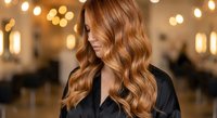 Professional woman with long wavy auburn hair in modern salon with warm bokeh lighting. Hair styling and beauty treatment concept for salon services.