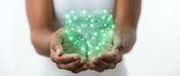Close-up of hands holding glowing green digital network particles and light effects, representing technology, data connection, innovation and digital transformation concepts.