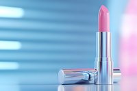 Pink lipstick in metallic silver case on soft blue and pink gradient background with reflective surface, elegant cosmetic product photography.