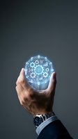 Close-up of male hand holding glowing sphere with digital brain, gears, and analytics icons representing artificial intelligence, machine learning, and business innovation technology.
