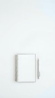 Open spiral notebook with blank white pages and silver pen on light gray background, ready for writing, planning, and note-taking.