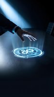 Hand reaching toward glowing blue holographic gear symbol on dark surface, representing technology, innovation, digital transformation, and futuristic business solutions.