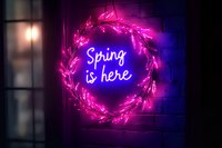 Glowing neon spring wreath sign with pink floral elements and blue text against dark background creates magical seasonal atmosphere for social media and decor.