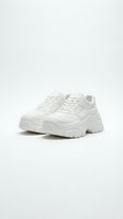 White chunky platform sneakers with thick wavy sole, isolated on light background. Trendy unisex footwear for fashion, retail, and lifestyle design use.