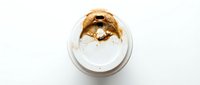 Overhead view of creamy peanut butter in white bowl on light background, suitable for food photography, recipe blogs, nutrition content, and culinary marketing materials.