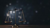 Golden brass scales of justice on dark background with bokeh lights for legal and law firm presentations.