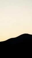 Silhouette of rolling hills against soft gradient sky transitioning from cream to pale yellow, creating serene landscape backdrop suitable for web design and digital projects.