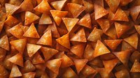 Crispy triangle corn tortilla chips arranged in rows creating geometric pattern background, golden brown color with visible seasoning and texture for food design.
