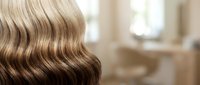 Glossy wavy hair with stunning ombre balayage, transitioning from dark brown to platinum blonde, captured in a bright salon interior.