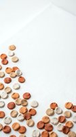 Scattered round confetti pieces in warm earth tones on white textured background with copy space for party decorations and craft projects.
