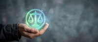 Businessman holding glowing scales of justice hologram symbol, representing legal services, law compliance, and ethical business practices for corporate solutions.