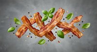 Crispy bacon strips with fresh basil leaves and peppercorns floating in mid-air against gray background for culinary and food advertising projects.
