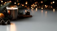 Glowing candle with pine branches, cinnamon sticks and tangerine against blurred golden bokeh lights on dark background. Cozy winter holiday atmosphere.