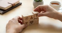 Hands arranging wooden blocks with eco-friendly symbols on desk workspace. Sustainable business concept for environmental planning and green strategy development.