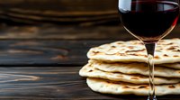 Stack of fresh homemade flatbread with glass of red wine on rustic wooden background. Traditional Mediterranean cuisine with dramatic lighting.